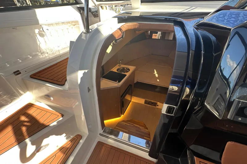 Slide: The Image of 2025 NX Boats 370 interior with wooden flooring and compact kitchenette. - 45