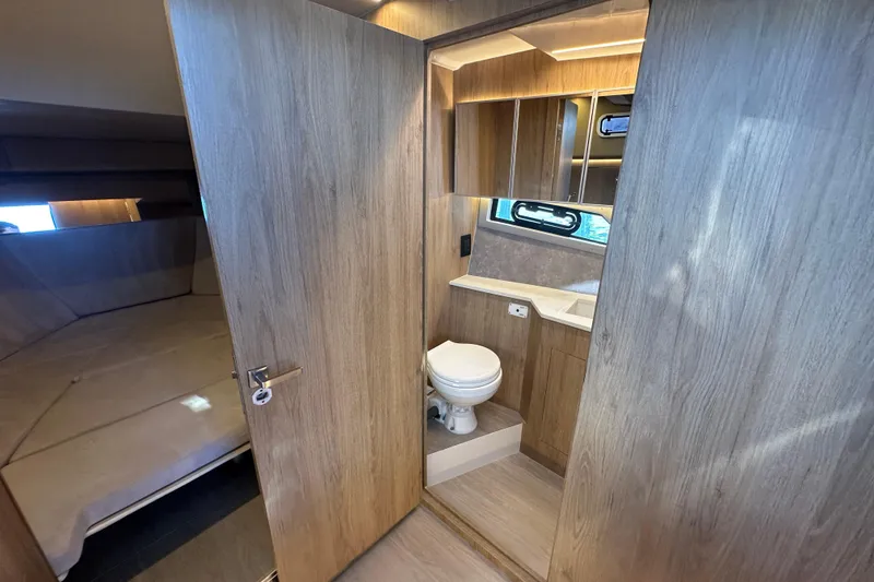 Slide: The Image of 2025 NX Boats 370 interior with wooden finish, featuring a compact bathroom and cozy sleeping area. - 52