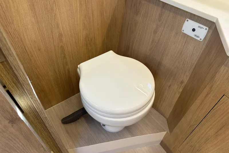 Slide: The Image of 2025 NX Boats 370 bathroom with modern toilet and wood paneling. - 56