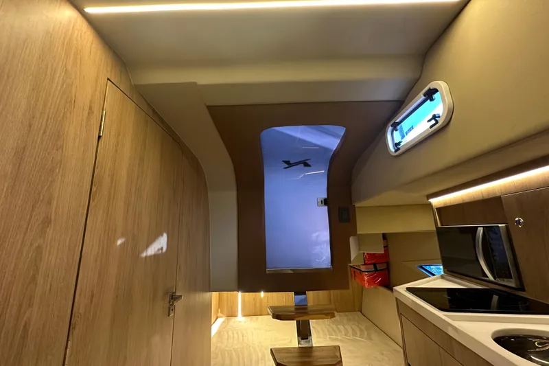Slide: The Image of Interior of 2025 NX Boats 370, featuring modern wood finishes and compact kitchen area. - 68