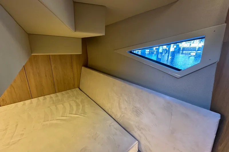 Slide: The Image of Interior cabin of 2025 NX Boats 370 with triangular window and cushioned seating. - 73