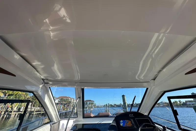 Slide: The Image of Interior view of 2025 NX Boats 370, showcasing helm and waterfront scenery. - 77