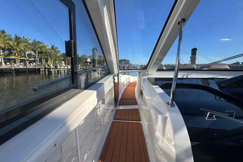 Slide: The Image of 2025 NX Boats 370 yacht with sleek design, docked by palm trees and clear blue sky. - 82