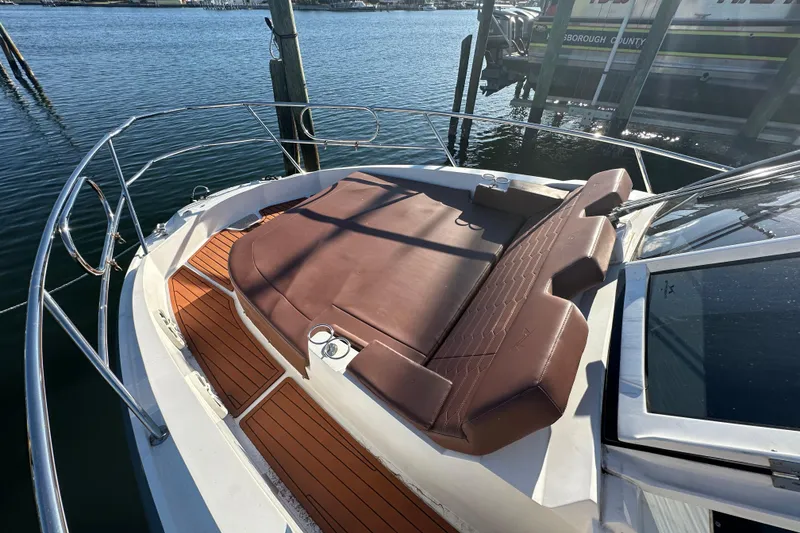 Slide: The Image of 2025 NX Boats 370 with brown sunbed on deck, docked by the water. - 86