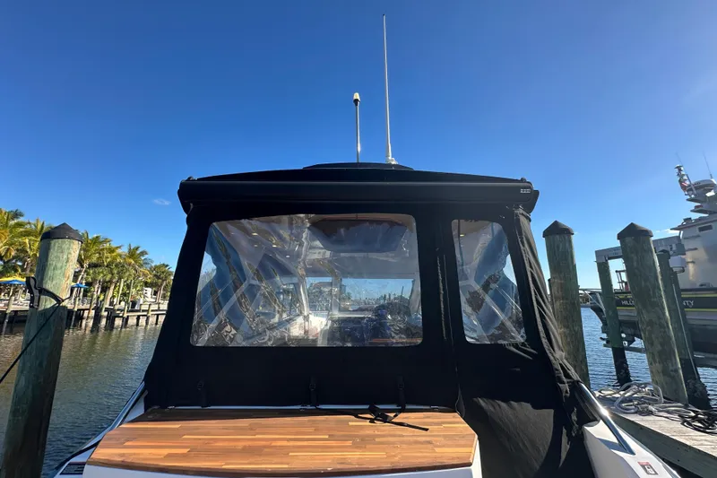 Slide: The Image of 2025 NX Boats 370 docked, featuring a sleek design and clear canopy under a bright blue sky. - 9