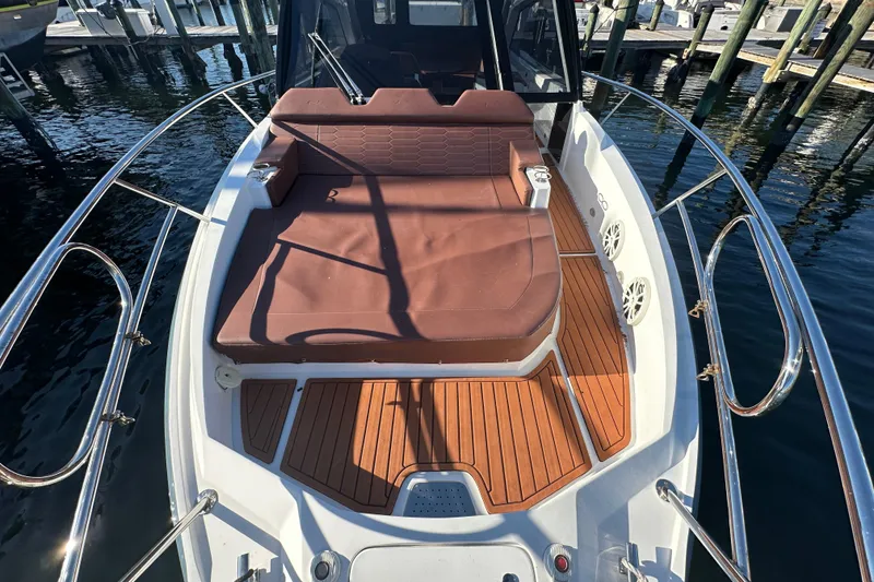 Slide: The Image of 2025 NX Boats 370 with brown seating and wooden deck, docked at marina. - 90