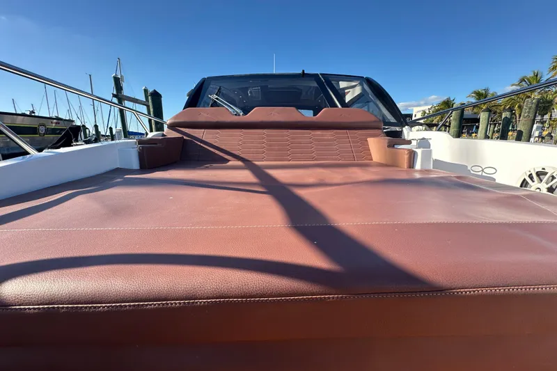 Slide: The Image of 2025 NX Boats 370 with brown leather seating, docked under clear blue sky. - 92
