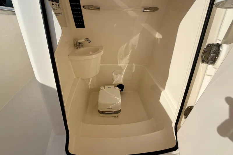 Slide: The Image of 2023 Cobia 262 Center Console boat interior with compact sink and portable toilet. - 28