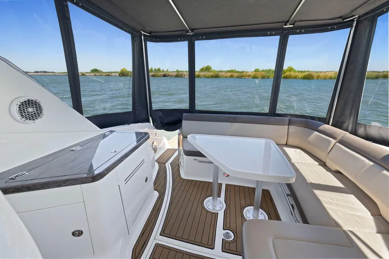 Slide: The Image of 2014 Sea Ray 350 Sundancer interior with seating and table, overlooking serene water view. - 15