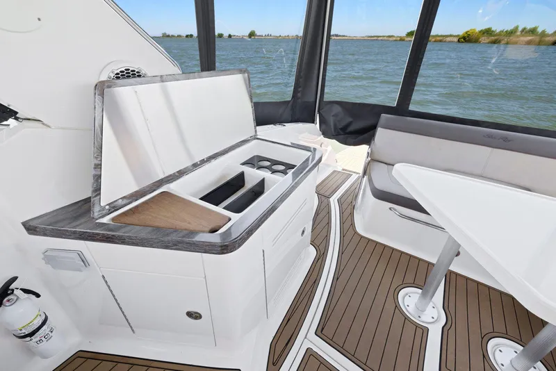 Slide: The Image of 2014 Sea Ray 350 Sundancer interior with kitchenette and seating, overlooking water. - 16