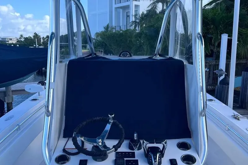 Slide: The Image of 2024 Contender 30 Tournament boat console with steering wheel and controls, docked near palm trees. - 21