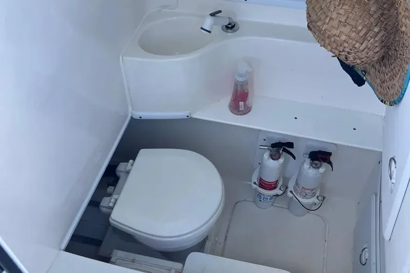 Slide: The Image of 2024 Contender 30 Tournament boat bathroom with toilet, sink, and fire extinguishers. - 8