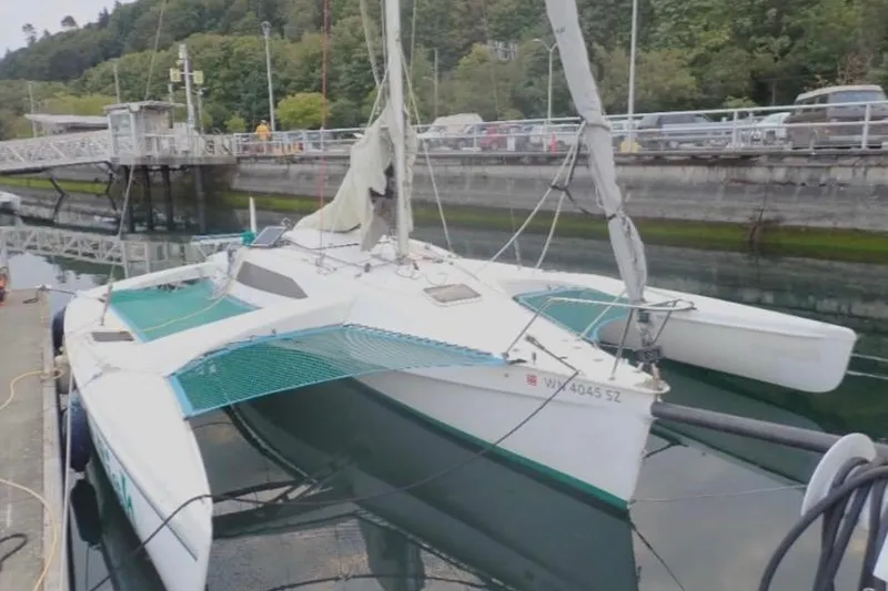 Slide: The Image of 2001 Corsair F-28 CC trimaran docked at a marina with lush greenery. - 3