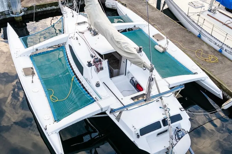 Slide: The Image of 2001 Corsair F-28 CC trimaran docked at marina, featuring green netting and white hull. - 7