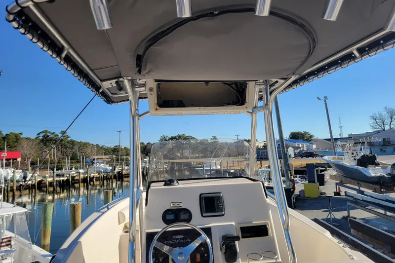 Slide: The Image of 2008 Cobia 235 Center Console boat at marina, featuring helm and T-top. - 3