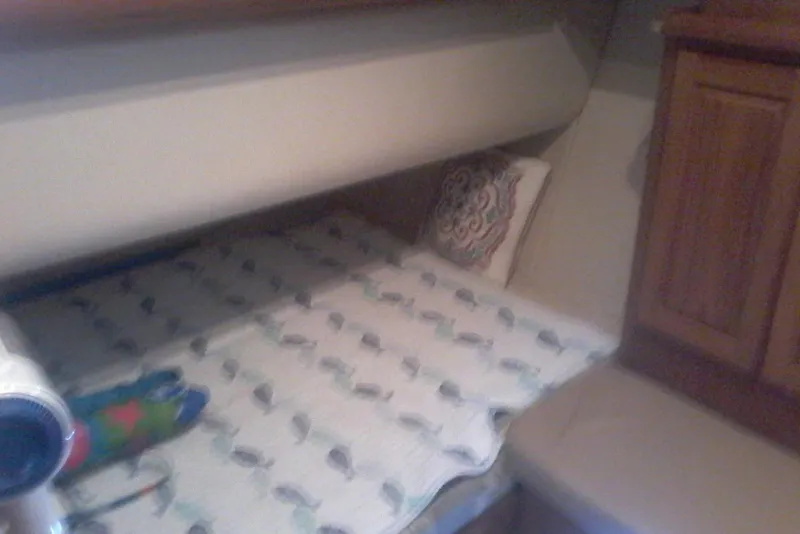 Slide: The Image of 1997 Mainship 350 cabin interior with bed, patterned bedding, and wooden cabinetry. - 30