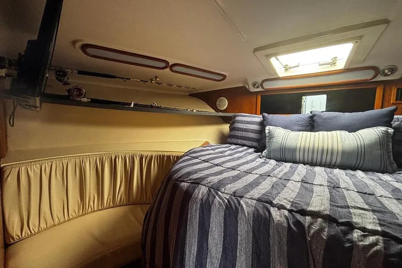 Slide: The Image of Cozy cabin interior of 2002 Luhrs 40 Open yacht with striped bedding and fishing rods. - 13