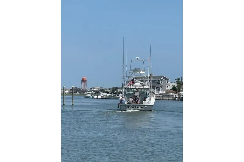 Slide: The Image of 2002 Luhrs 40 Open boat cruising in a coastal waterway, with houses and a water tower in the background. - 37