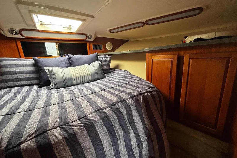 Slide: The Image of Cozy cabin interior of 2002 Luhrs 40 Open yacht with striped bedding and wooden cabinets. - 9