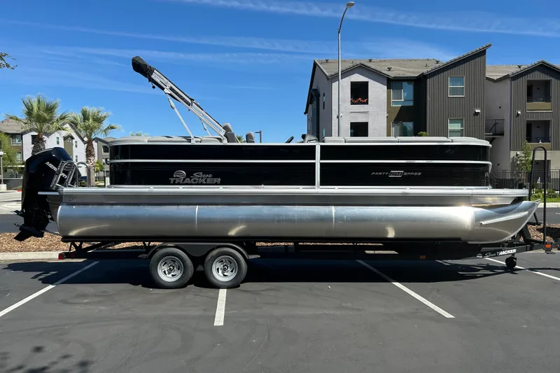 The Image of 2026 Sun Tracker Party Barge 24 XP3 pontoon boat on trailer in parking lot. - 0