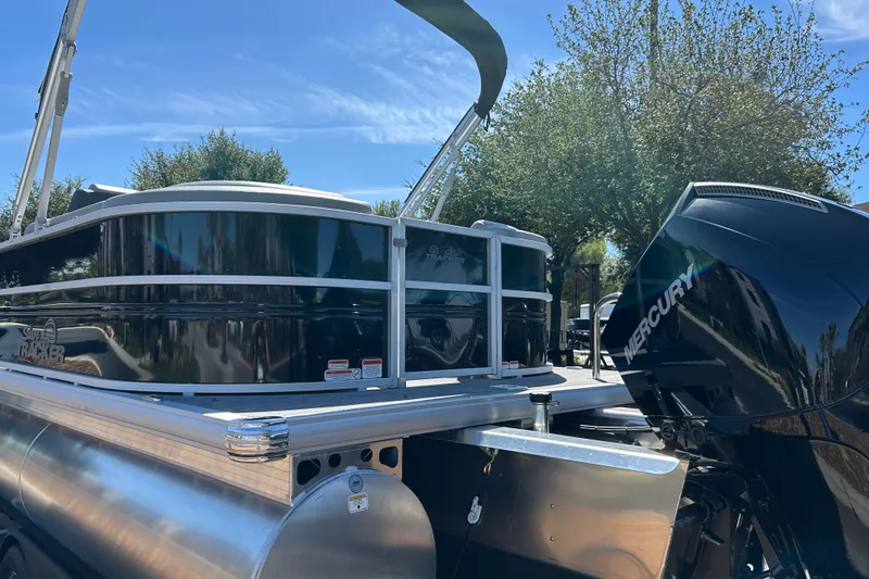 Slide: The Image of 2026 Sun Tracker Party Barge 24 XP3 pontoon boat with Mercury engine, under clear blue sky. - 25
