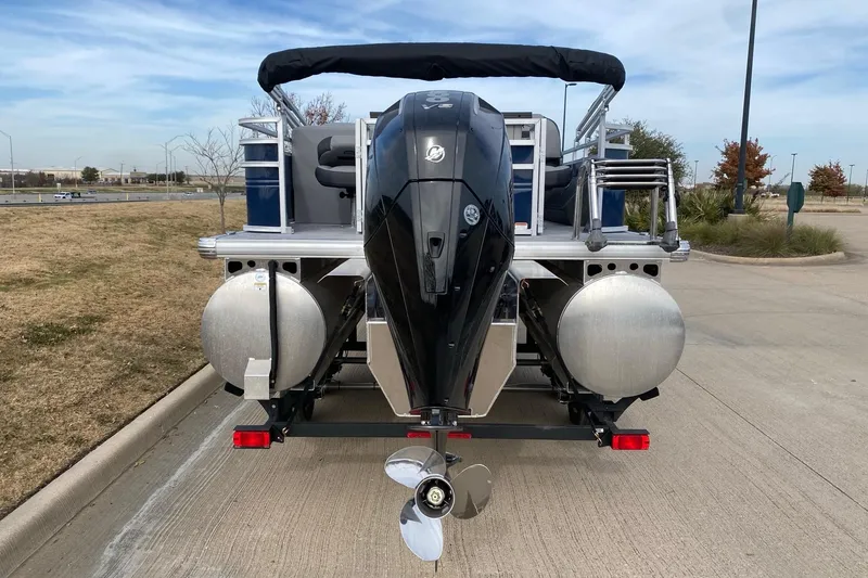 Slide: The Image of 2026 Sun Tracker SportFish 22 XP3 pontoon boat with powerful outboard motor, parked on pavement. - 11