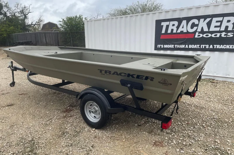 Slide: The Image of 2026 Tracker Grizzly 1754 Utility boat on trailer, displayed outdoors near Tracker Boats sign. - 2