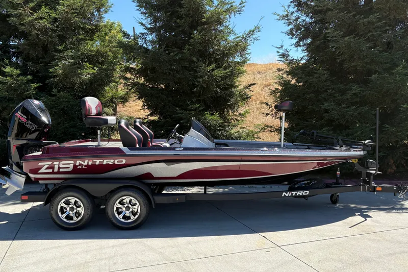 The Image of 2026 Nitro Z19 XL boat on trailer, parked outdoors near trees. - 0