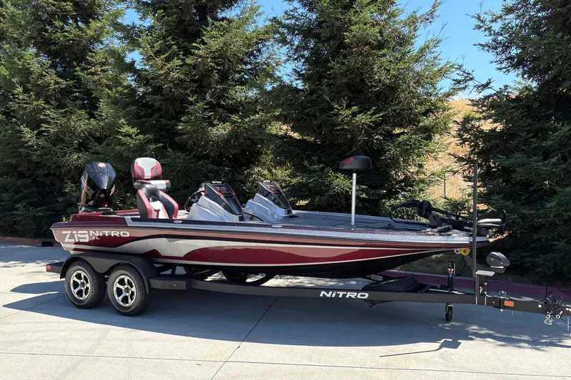 Slide: The Image of 2026 Nitro Z19 XL boat on trailer, parked outdoors near trees. - 2