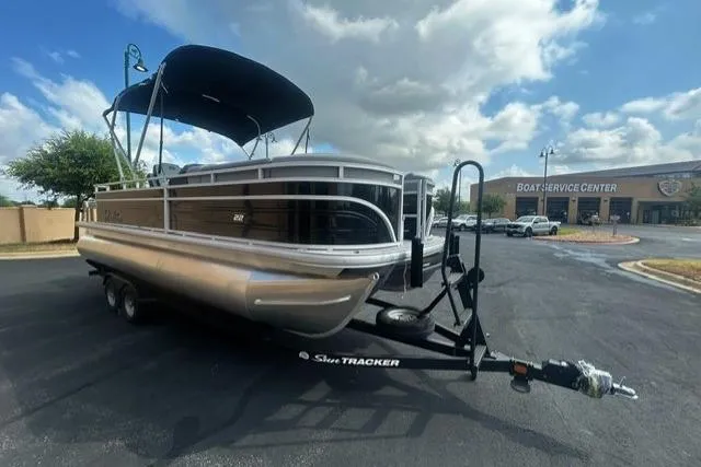 Slide: The Image of 2026 Sun Tracker SportFish 22 XP3 pontoon boat on trailer, parked near boat service center. - 2
