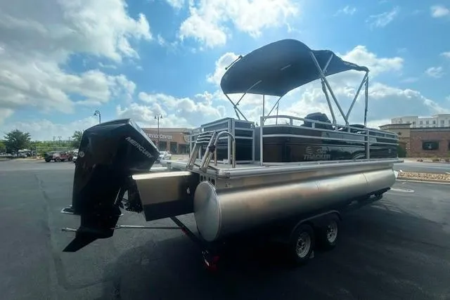 Slide: The Image of 2026 Sun Tracker SportFish 22 XP3 pontoon boat with canopy, parked outdoors under a cloudy sky. - 3