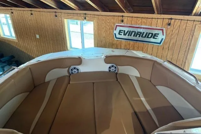 Slide: The Image of 2023 NauticStar 203 DC boat interior with tan seating, Evinrude sign in background. - 13