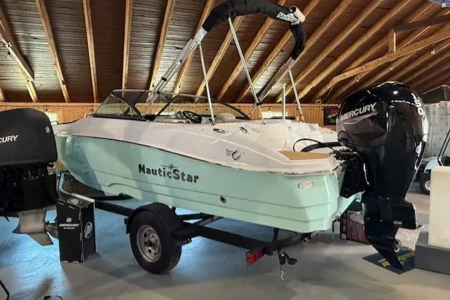 Slide: The Image of 2023 NauticStar 203 DC boat with Mercury outboard motor in a wooden-roofed showroom. - 4