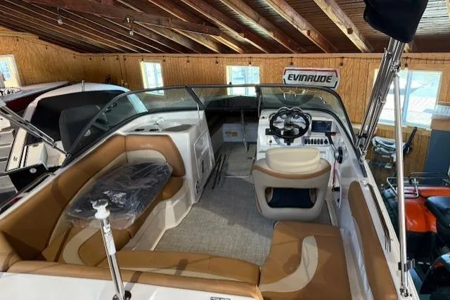 Slide: The Image of 2023 NauticStar 203 DC boat interior with tan seating, steering wheel, and Evinrude sign. - 6