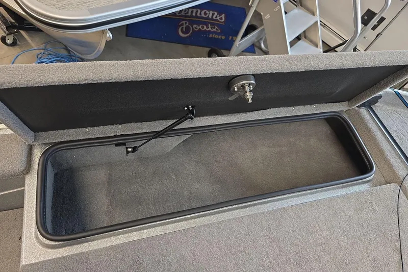 Slide: The Image of 2023 Bass Cat Caracal storage compartment with open lid and secure latch mechanism. - 16