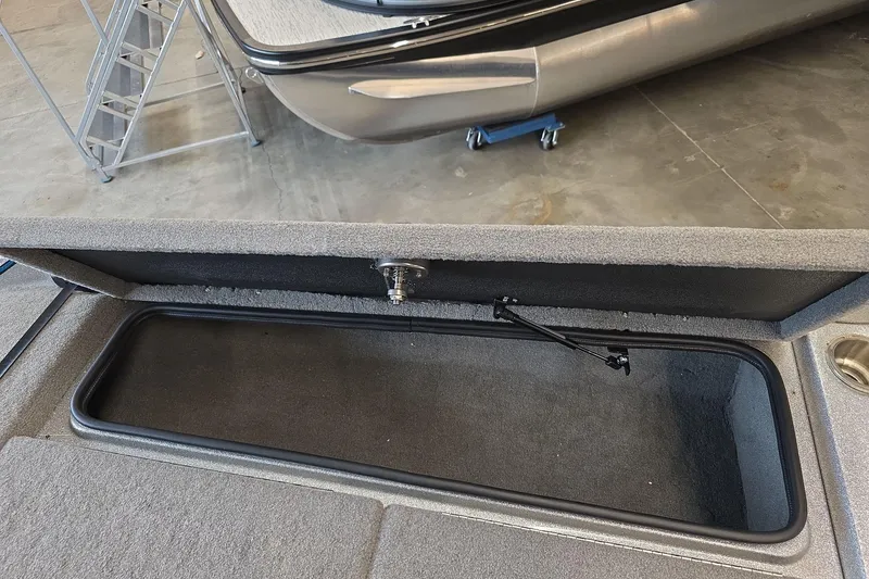 Slide: The Image of 2023 Bass Cat Caracal boat storage compartment with open lid in a garage setting. - 18