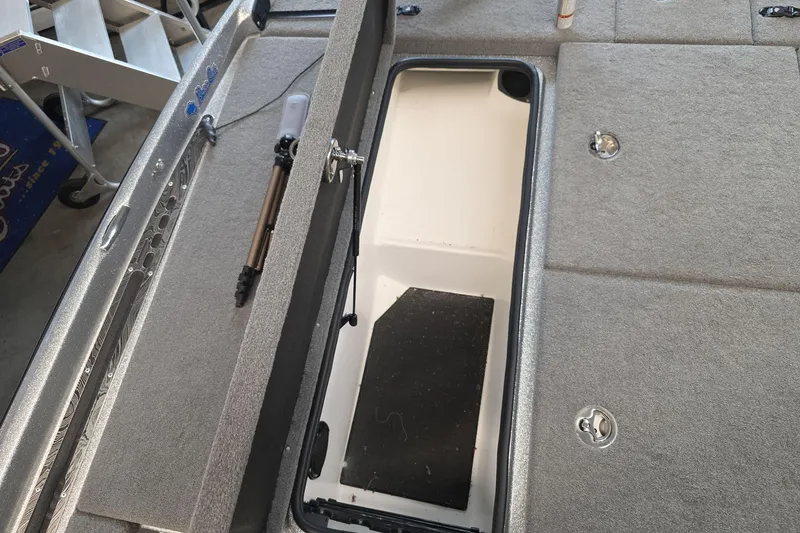Slide: The Image of 2023 Bass Cat Caracal boat storage compartment with open lid and carpeted interior. - 19