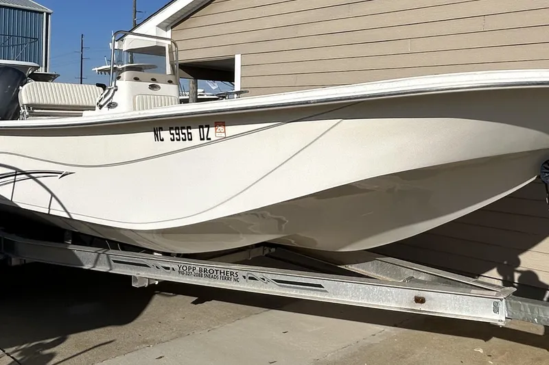The Image of 2014 Carolina Skiff 258 DLV boat on trailer, parked beside a building. - 1