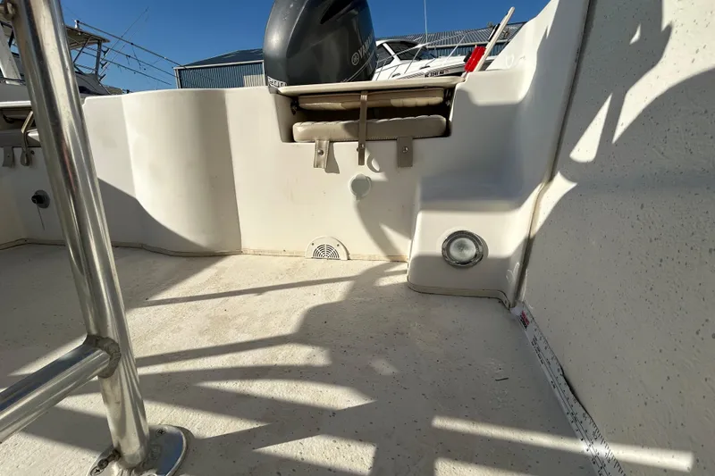 Slide: The Image of 2014 Carolina Skiff 258 DLV boat interior with motor and seating, under bright sunlight. - 20