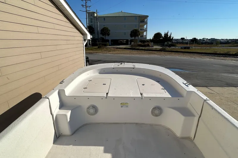 Slide: The Image of 2014 Carolina Skiff 258 DLV boat deck, parked near a building, under clear sky. - 6