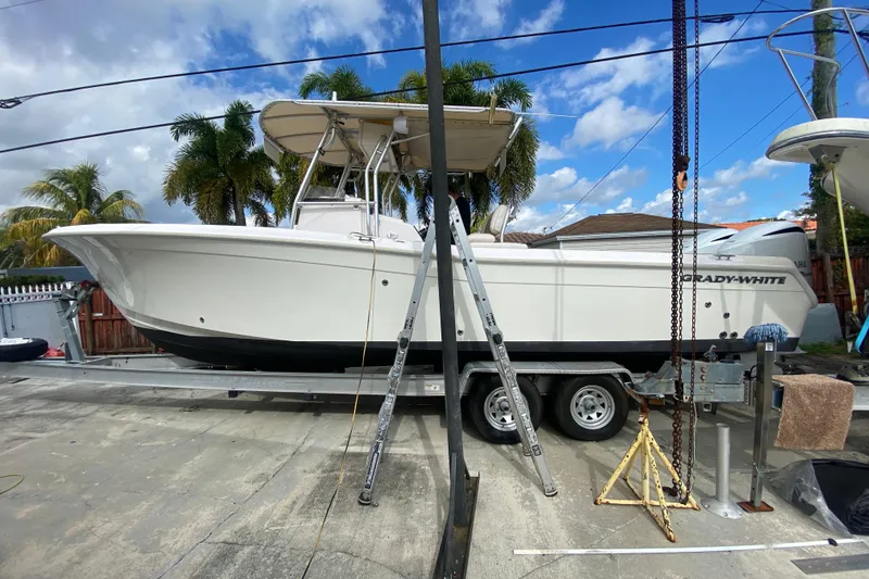 Slide: The Image of 2004 Grady-White Canyon 283 boat on trailer, parked outdoors under blue sky. - 13