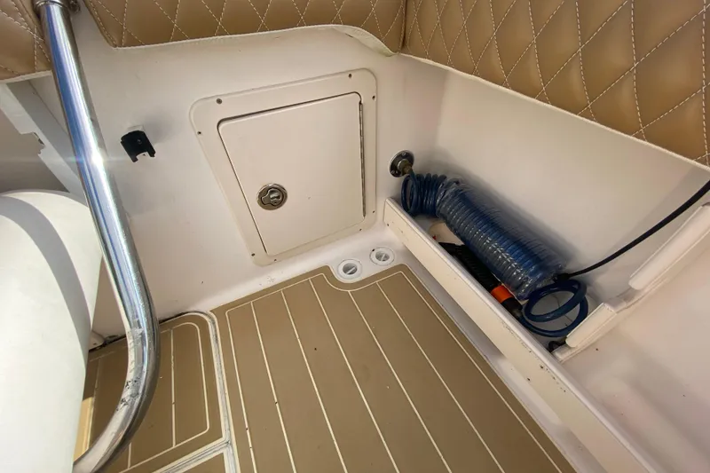 Slide: The Image of 2004 Grady-White Canyon 283 boat interior with storage compartment and coiled hose. - 31