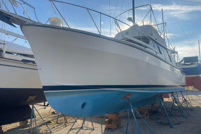 Slide: The Image of 1986 Mainship Mark III Motor Cruiser on stands, side view under clear sky. - 2