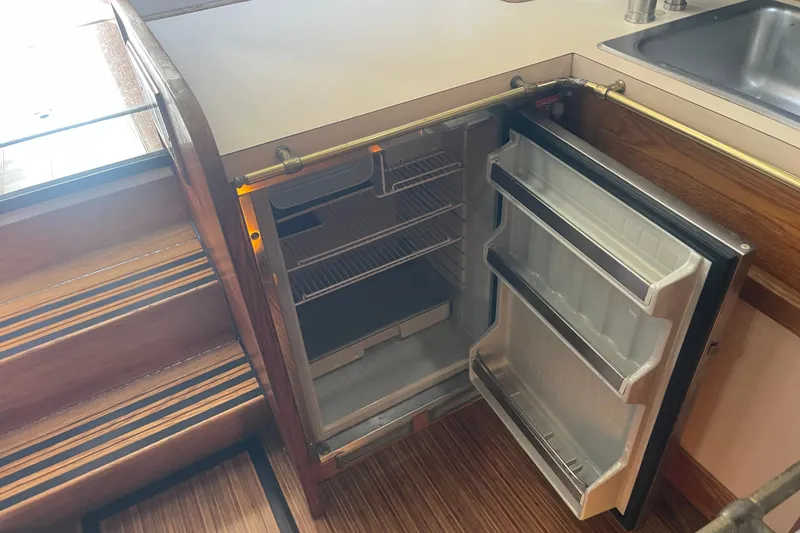 Slide: The Image of 1986 Mainship Mark III Motor Cruiser interior with open fridge and wooden stairs. - 26