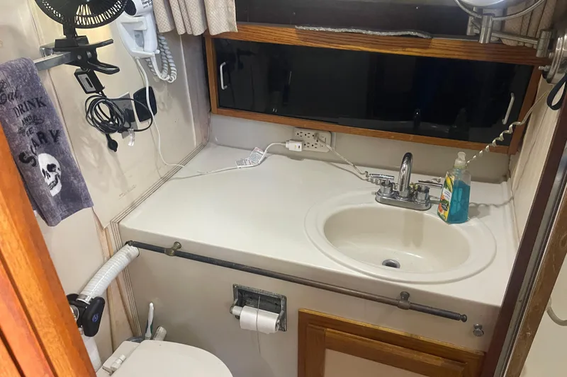 Slide: The Image of 1986 Mainship Mark III Motor Cruiser bathroom with sink, mirror, and toiletries. - 27