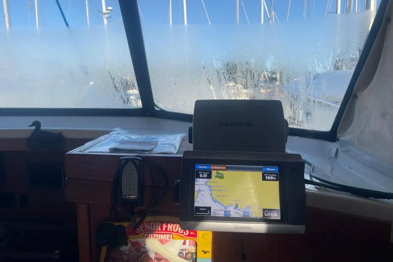 Slide: The Image of 1986 Mainship Mark III Motor Cruiser cockpit with Garmin GPS, foggy windows, and nautical charts. - 31