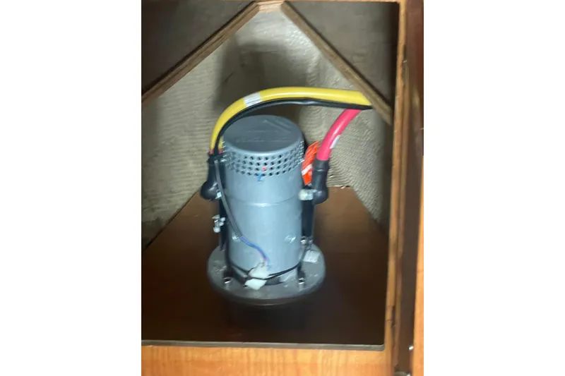 Slide: The Image of 1986 Mainship Mark III Motor Cruiser engine component with wiring in wooden compartment. - 49