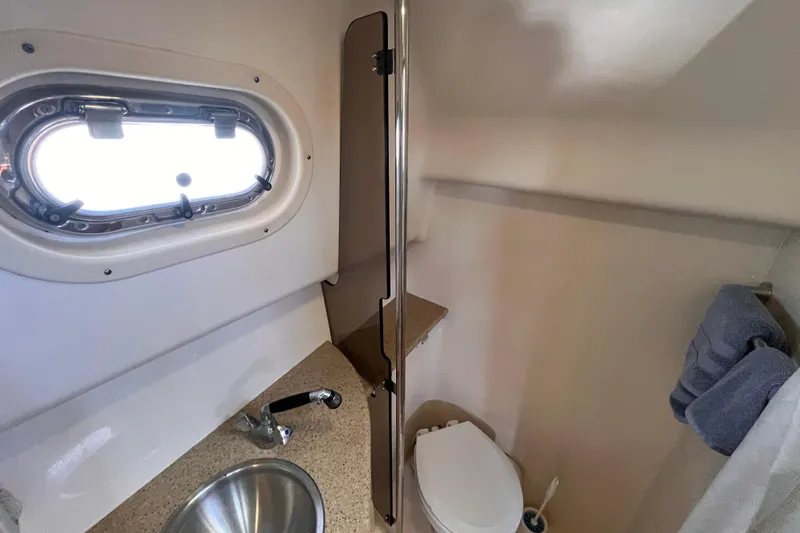 Slide: The Image of 2009 Mainship Pilot 31 boat bathroom with sink, toilet, and porthole window. - 10