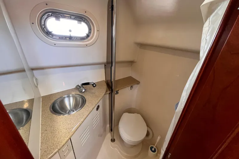 Slide: The Image of 2009 Mainship Pilot 31 boat bathroom with sink, toilet, and porthole window. - 11