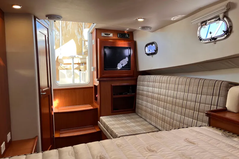 Slide: The Image of 2009 Mainship Pilot 31 cabin interior with plaid seating, TV, and portholes. - 19